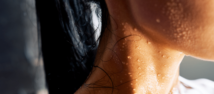 Close up photo of a woman with sweat beading on her neck and cheek