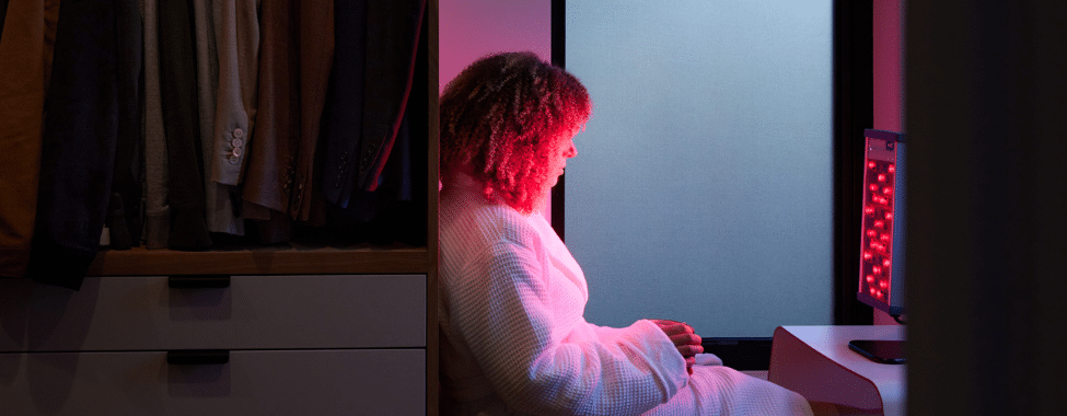 Woman in Small Wellness Room Using Personal Red Light Device